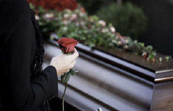 a woman with a rose stands by the coffin