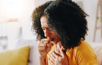 Home, sick and woman with chest pain, cough and virus with asthma, allergy and influenza in lounge. Apartment, illness and person on couch, viral infection and disease with sinus, covid and fever