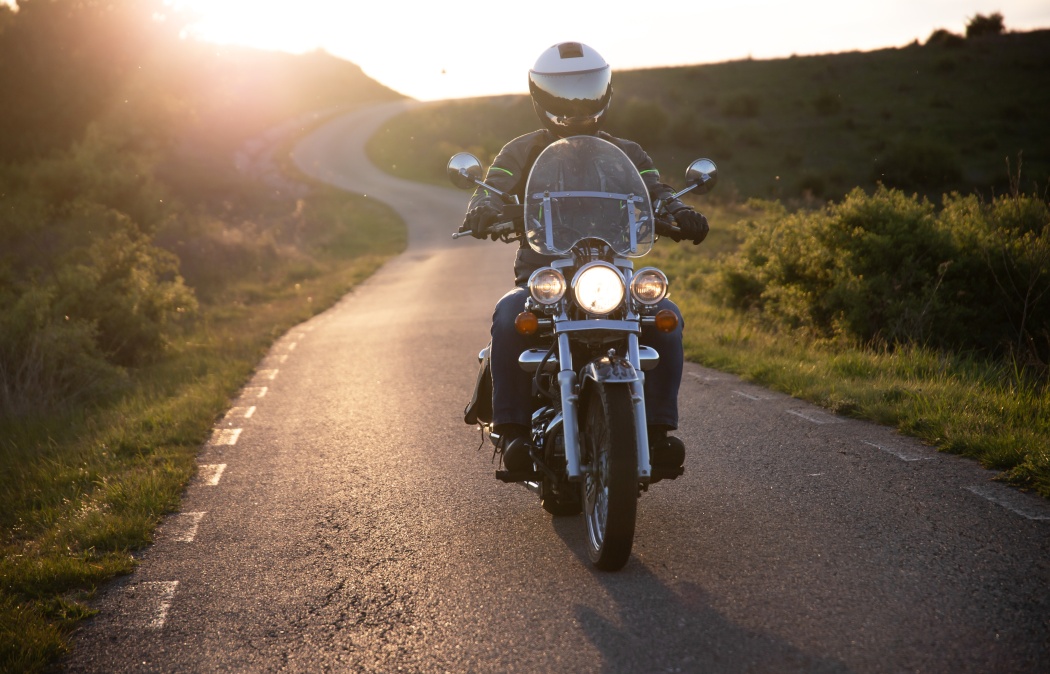 Motorcycle rider on the road in sunset light. Travel and sport, speed and freedom concept.